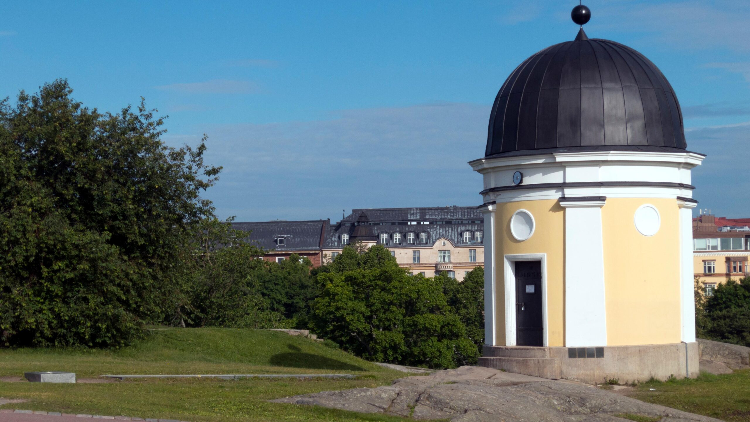 Kaivopuiston tähtitorni kesäisessä maisemassa. Torni on keltavalkoinen ja sen kupu on musta.