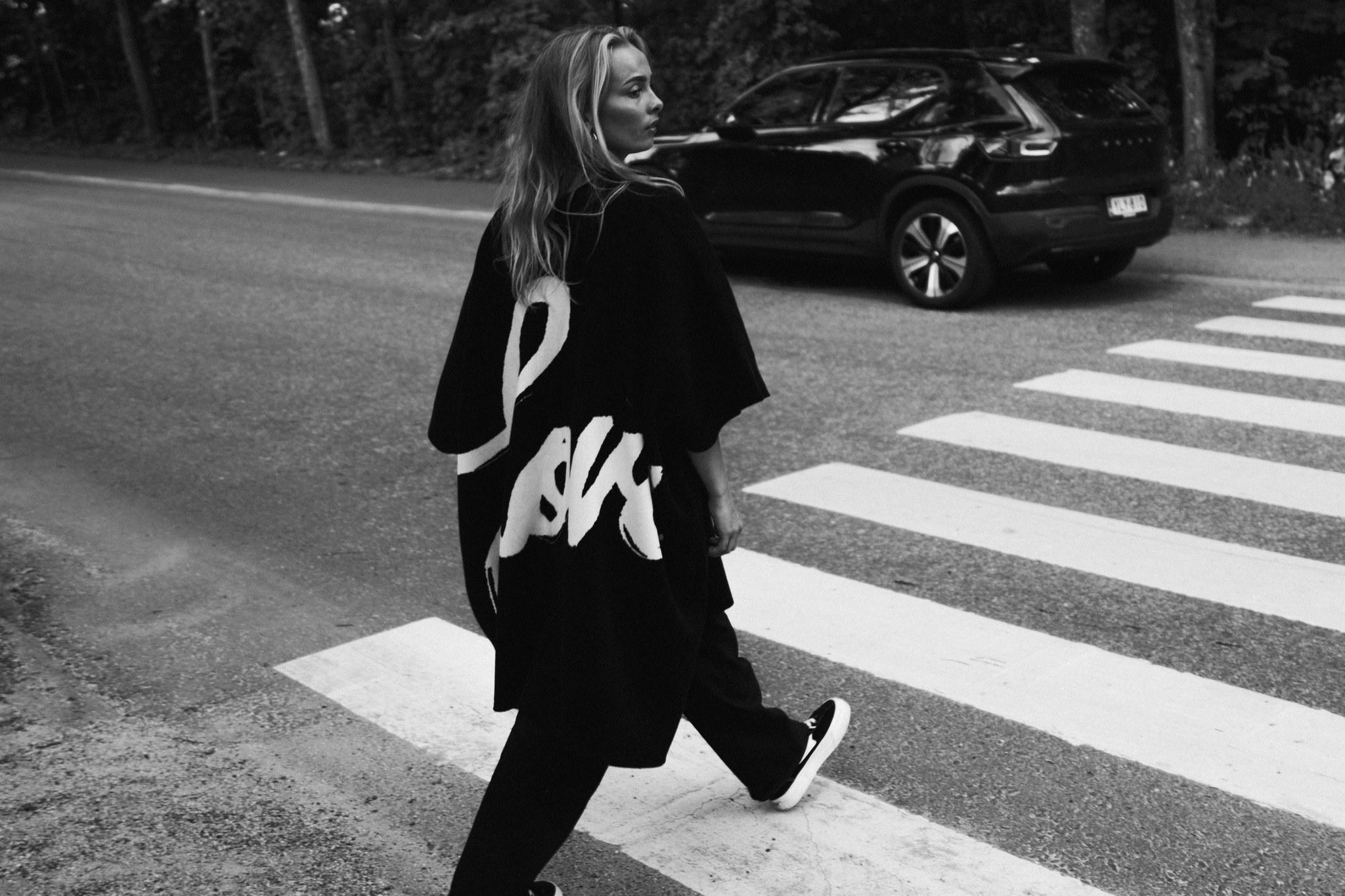 A black and white photo of a person crossing the street.