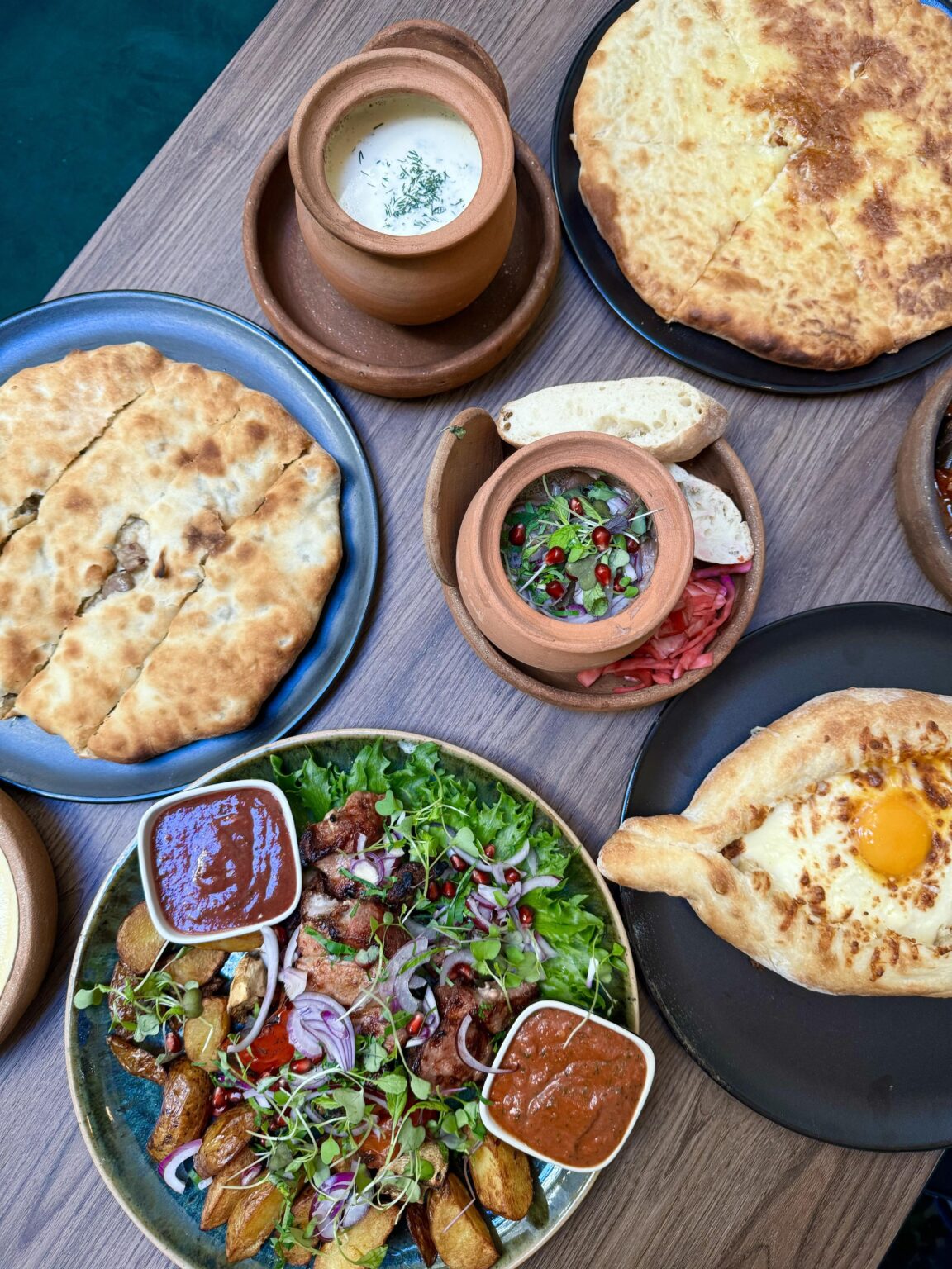 Georgian dishes. Grilled skewers with Georgian sauces, pelmeni, khachapuri, lobio, and meat bread with herbs.