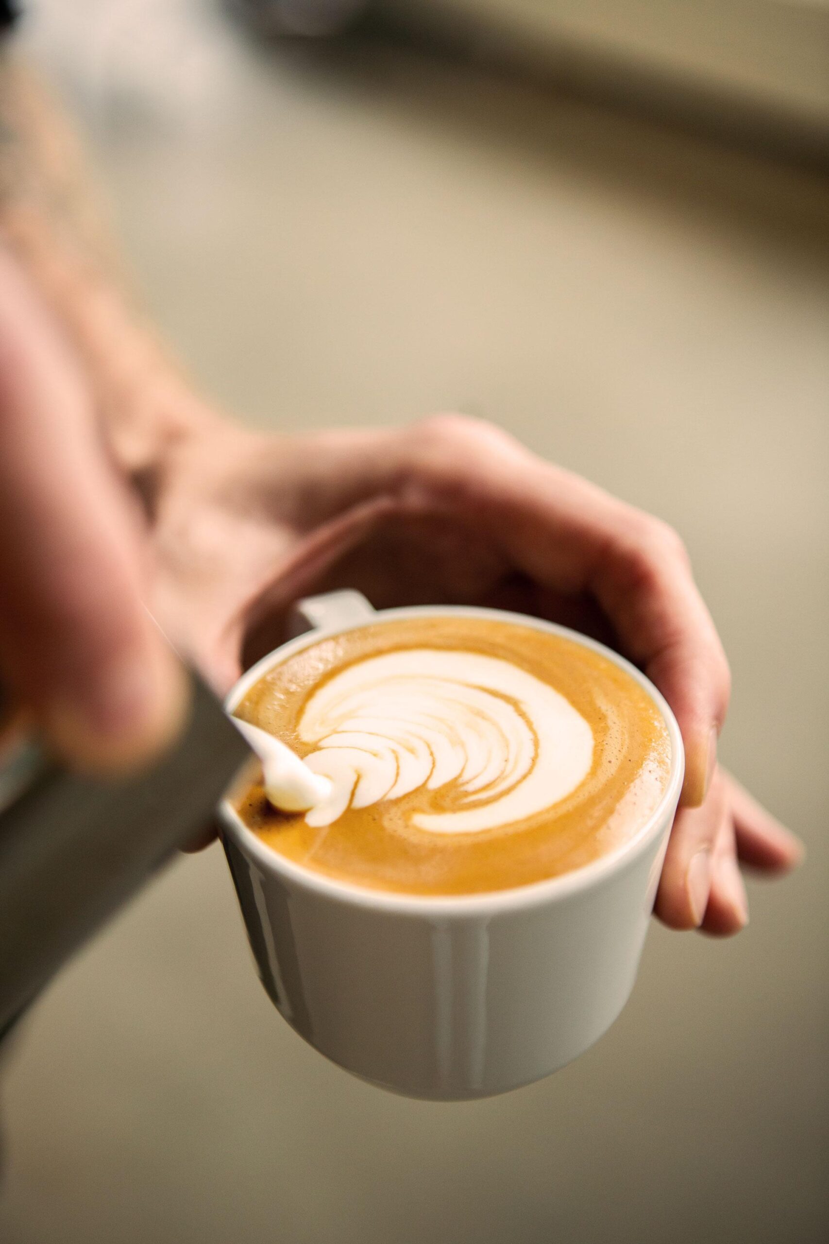 Johan & Nyström. A person is holding a coffee cup in their hands.