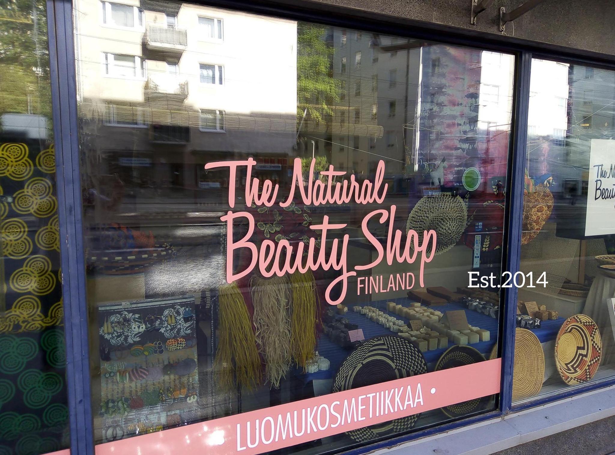 Natural Beauty Shop Finlandin kivijalkamyymälä ulkoapäin katsottuna. Myymälän ikkunassa lukee myymälän nimi vaaleanpunaisilla kirjaimilla.