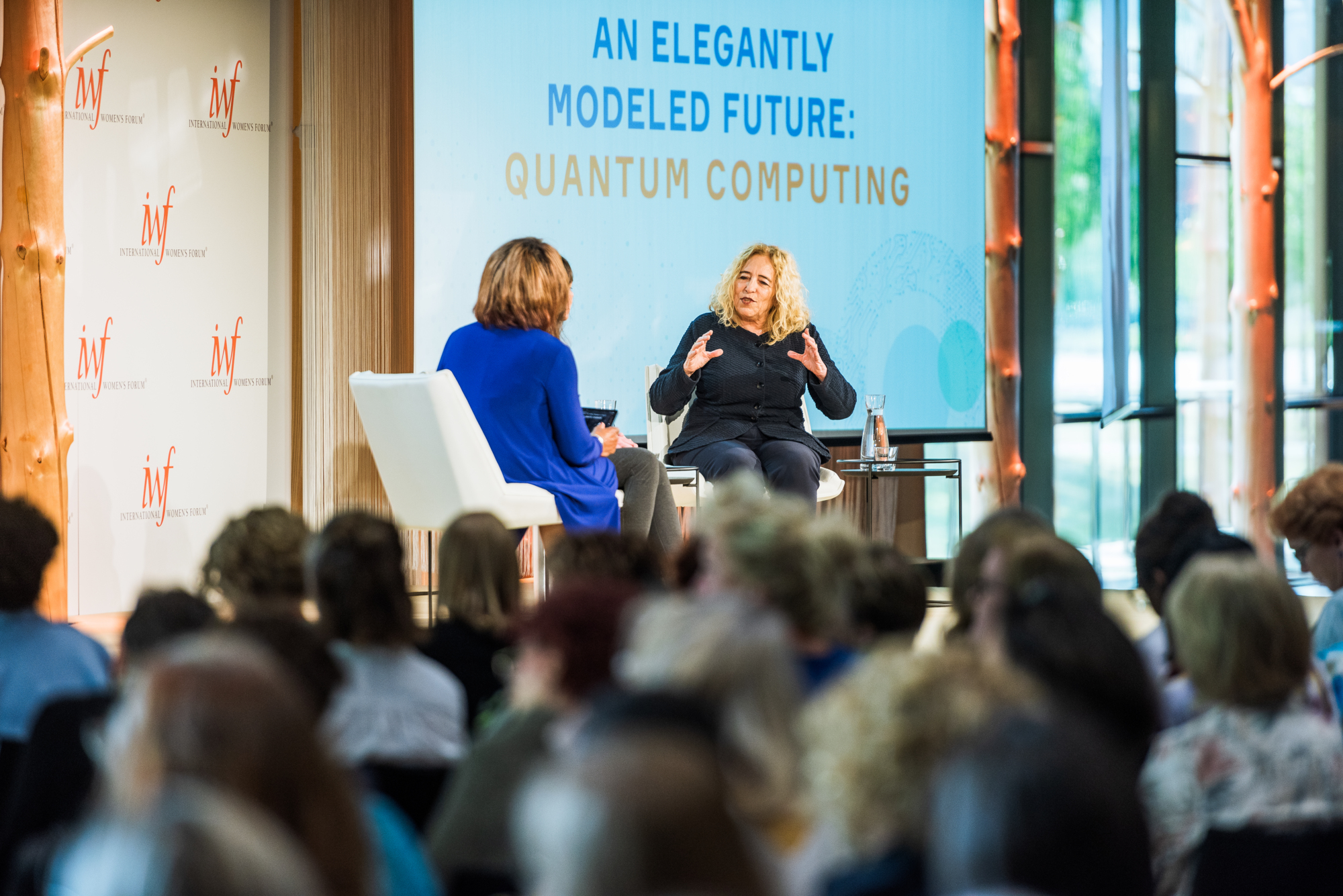 a group of women sitting in chairs talking to a crowd International Women's Forum meet in Helsinki