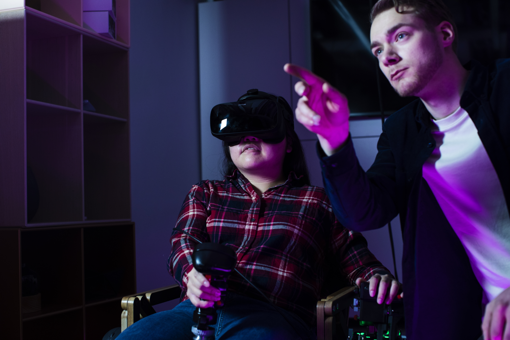 a man pointing at a woman in a wheelchair with VR glasses testing artificial intelligence