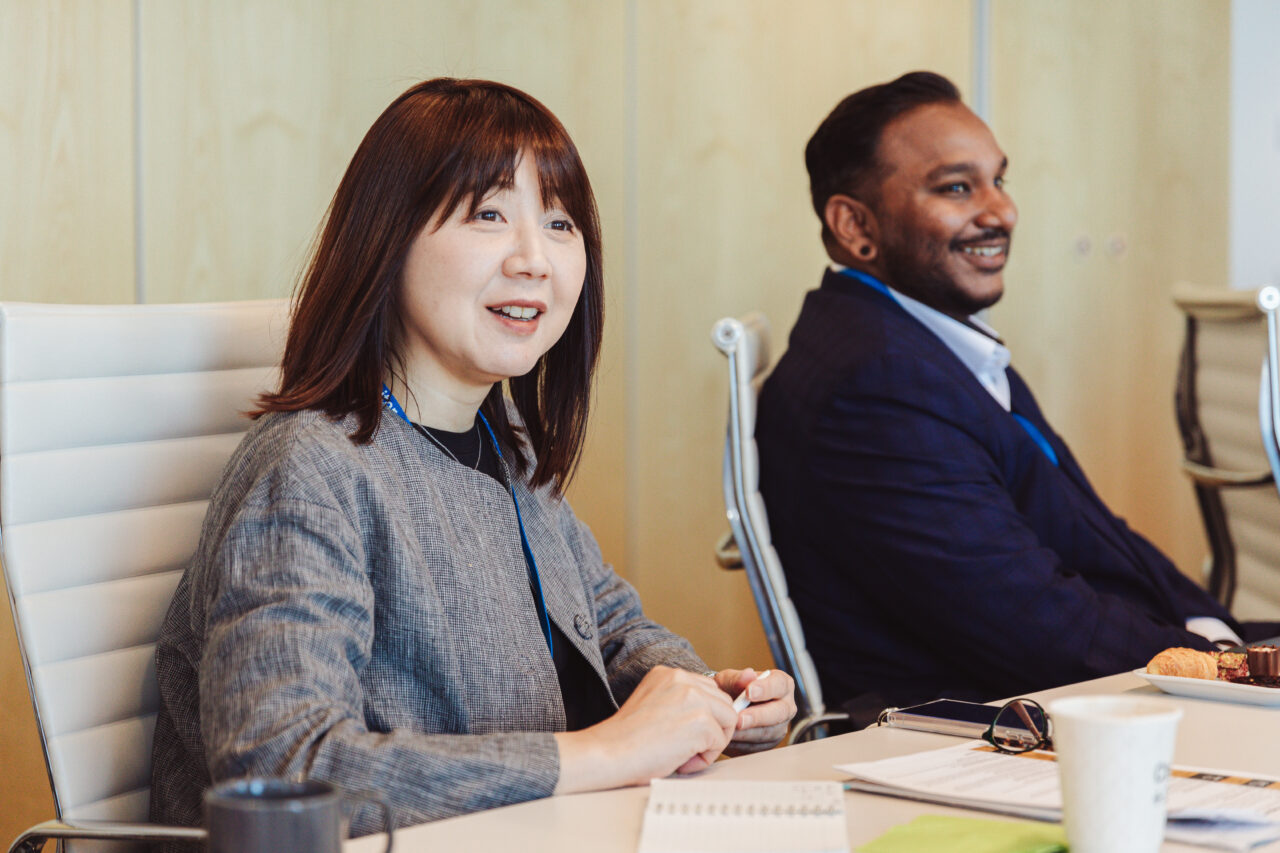 Woman and man at a table in an office smiling during a business meeting about tech innovation in Helsinki.