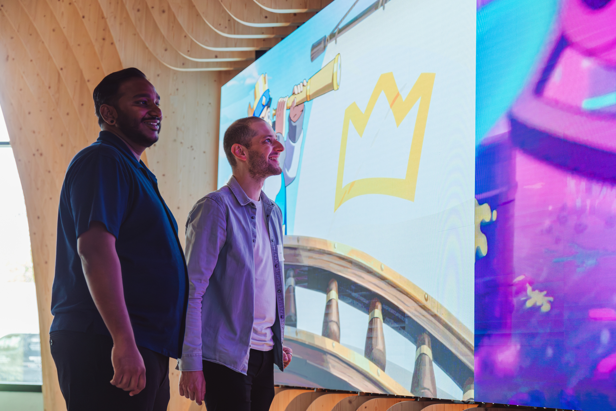 two men standing in front of a large screen