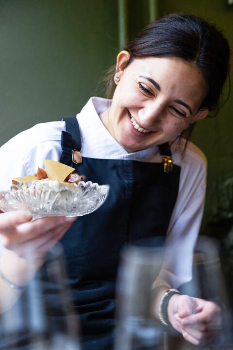 a woman smiling at a plate of food