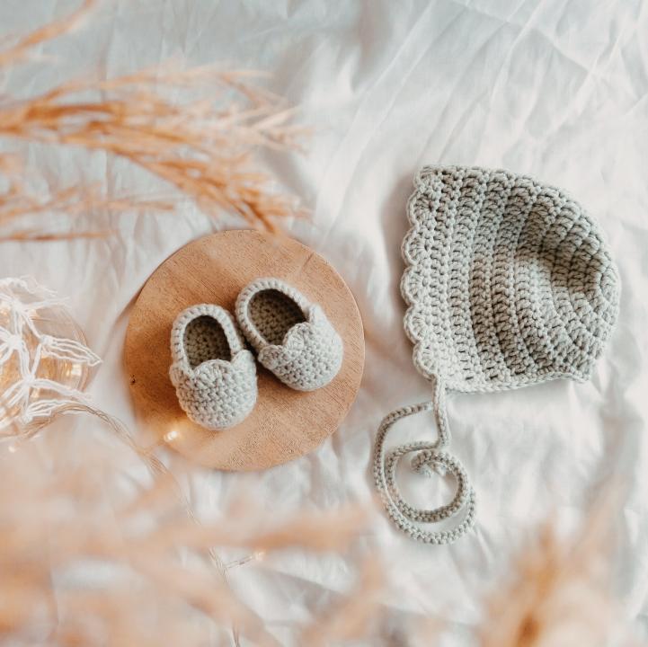 a baby shoes and a hat on a wooden plate