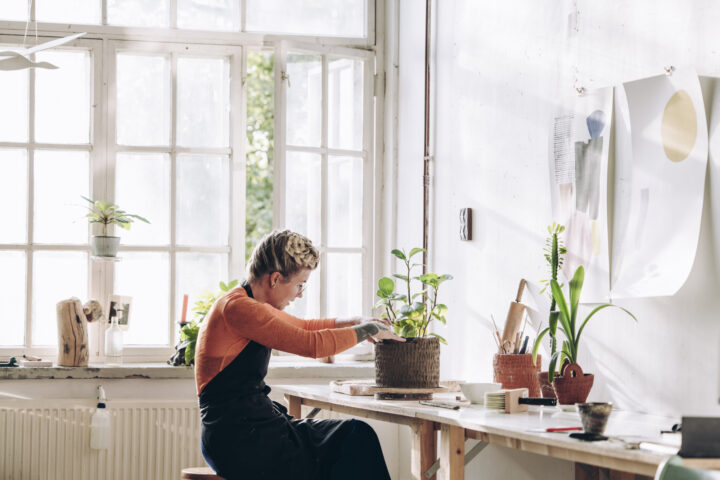 a woman sitting at a table with a plant in a pot