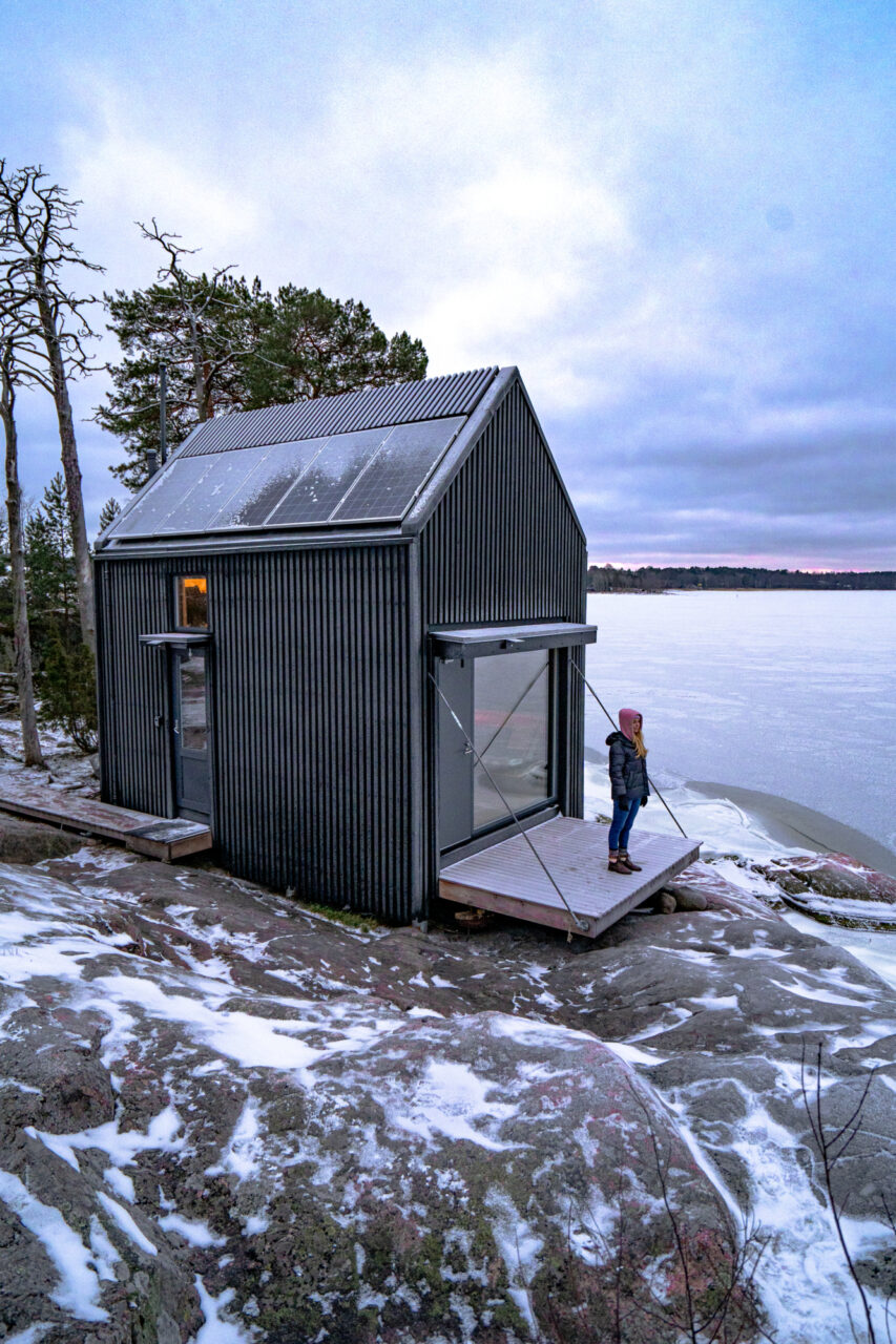 a person standing on a porch of a small house in Majamaja Helsinki